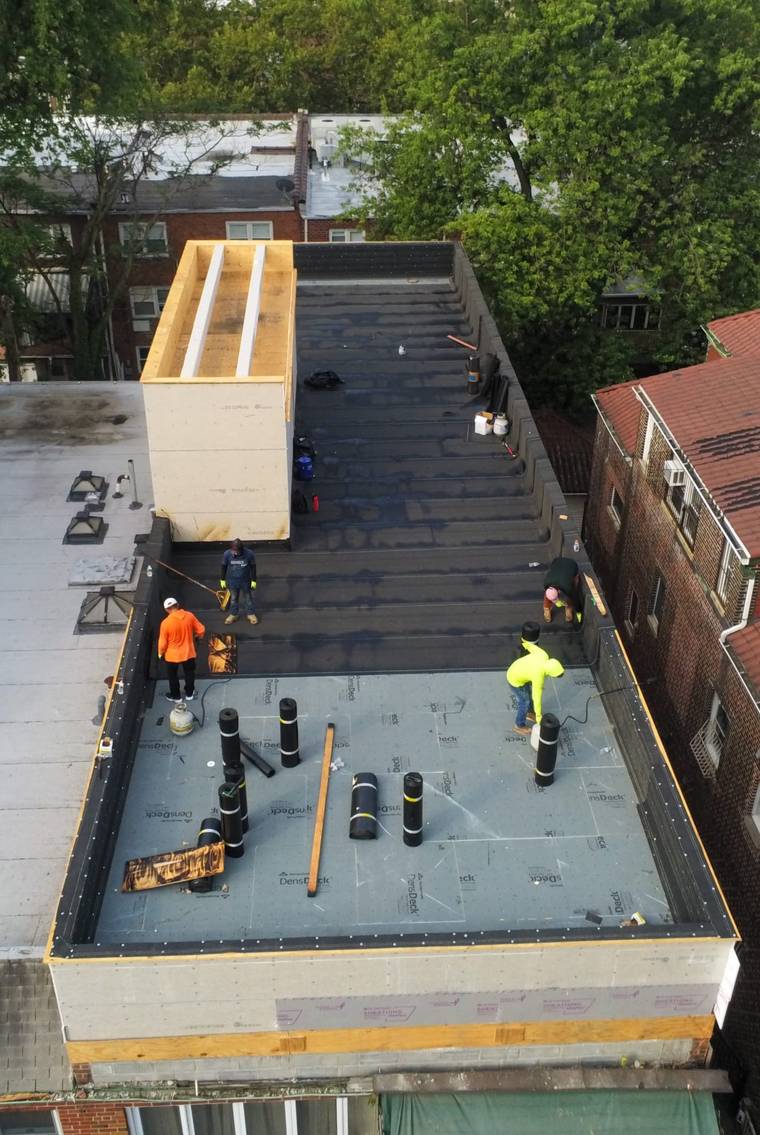 Crew installing a flat roof on new construction